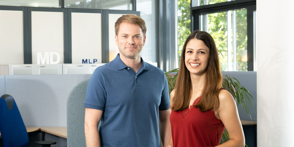 Kollegen stehen im Büro und lachen in die Kamera 